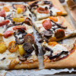 mushroom and cherry tomato pizza 3_4 close up with pieces horizontal