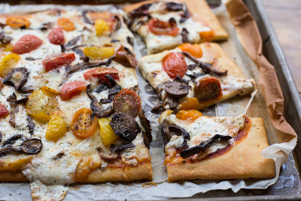 mushroom and cherry tomato pizza 3_4 close up with pieces horizontal