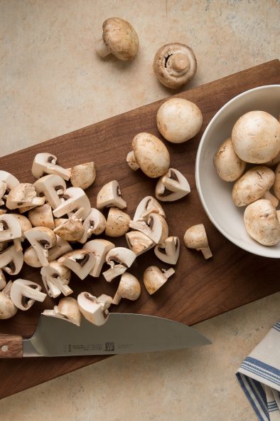 Quartered and whole mushrooms on a cutting board.