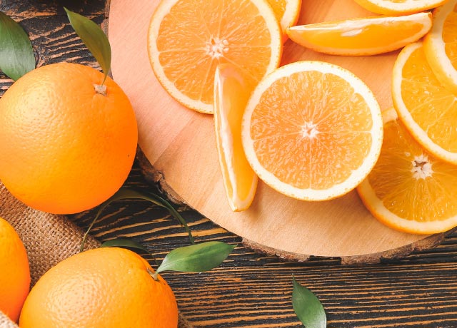 Whole navel oranges next to a variety of sliced oranges.