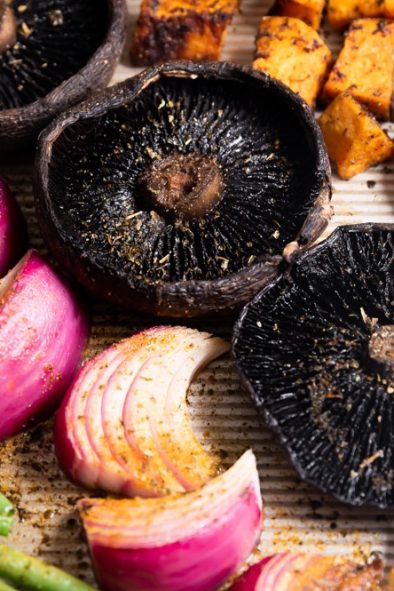 Mushrooms, red onions, green beans, and potatoes on a sheet pan.