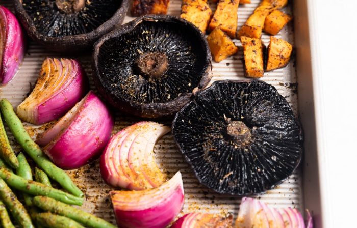 Mushrooms, red onions, green beans, and potatoes on a sheet pan.