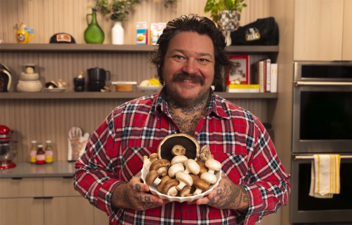 Matty Matheson smiling in the kitchen holding a bowl of fresh mushrooms
